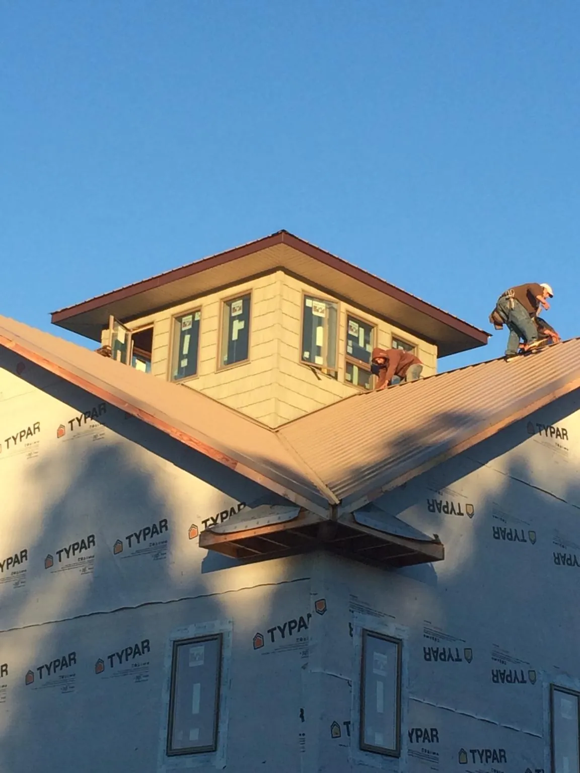 Roofers working around a rooftop cupola on a new metal roof at sunset — Roof Waterproofing in Lakeville by Roofing Brothers